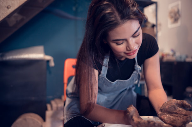 陶艺艺术家，年轻的女性，冷静而细致地制作一件陶土，为了制作出最具吸引力的作品，图片下载