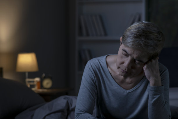 抑郁的亚洲老年妇女坐在床上无法入睡，因为失眠图片下载