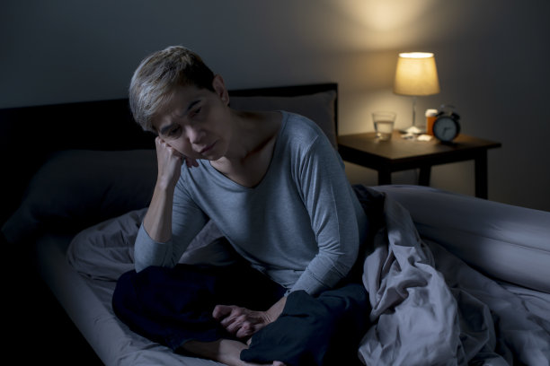 抑郁的亚洲老年妇女坐在床上无法入睡，因为失眠图片下载