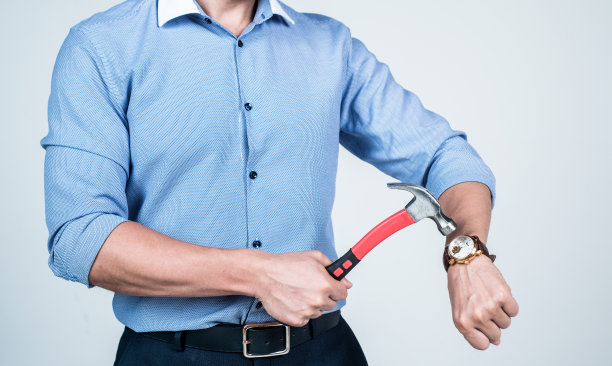 男人用锤子看断腕表，敲钟图片下载