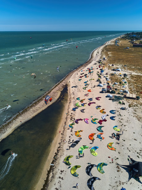 在有风的日子，在风筝冲浪点，从上面看，明亮多彩的风筝停在海滩上。很多放风筝的降落伞都在海岸线上。极限水上运动。航拍无人机照片。图片下载
