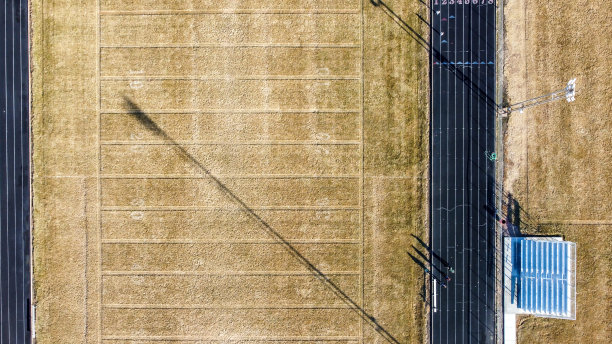 空中无人机拍摄的一个足球场，棕色的草地和沿着两边的跑道。图片下载