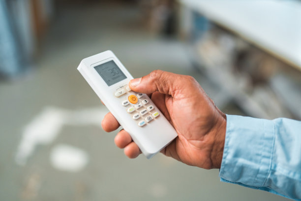 西班牙裔男性正在使用空调遥控器图片下载