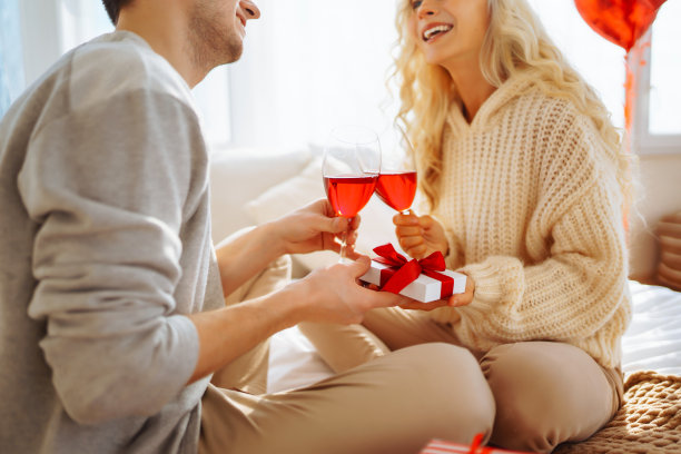 年轻情侣在家里喝红酒庆祝情人节。图片下载