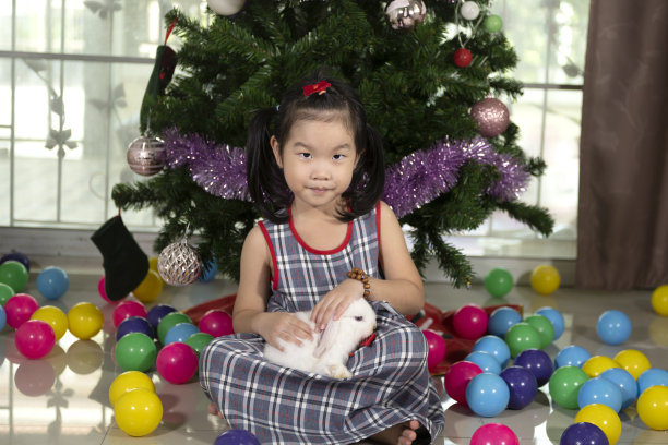 一只可爱的兔子躺在一个可爱的亚洲小女孩的腿上。有一颗温柔的心的孩子喜欢动物。图片下载