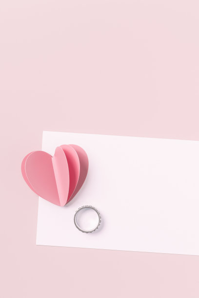 粉红色的纸心和空白的白纸卡片和结婚戒指在粉红色的背景。简约风格的爱情笔记，柔和的颜色，模拟情人卡，求婚。浪漫的概念图片下载
