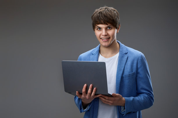 白人年轻男子使用笔记本电脑孤立在灰色背景图片下载