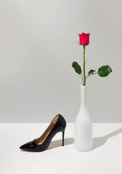 玫瑰花，香槟瓶和黑色女鞋的创意概念。白色和灰色背景的可持续时尚理念。最小的情人节概念。图片下载