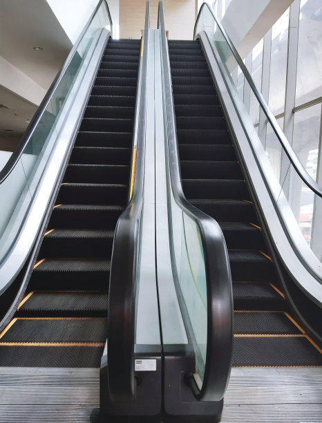 大楼内的自动扶梯，玻璃窗旁边图片下载