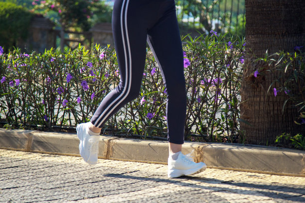 一个穿着白色运动鞋的女人的腿在美丽的灌木丛中沿着岩石小径奔跑图片下载