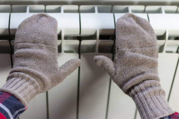 冬天，一个女孩在家里的暖气片上取暖。图片下载