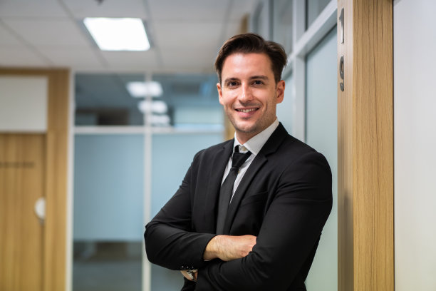 白人英俊的商人在办公室工作的肖像。有魅力的年轻职业男性员工，他们自信地站在公司里，微笑着看着镜头图片下载