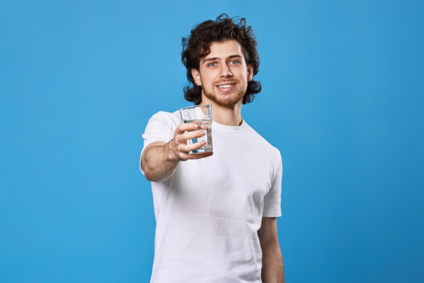穿着白t恤的帅哥展示着一杯水图片下载