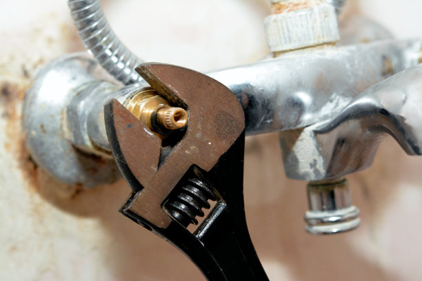 水管工正在修理淋浴水龙头的问题，用活动扳手工具旋转阀芯主体以更换，家庭水暖和维护概念背景图片下载