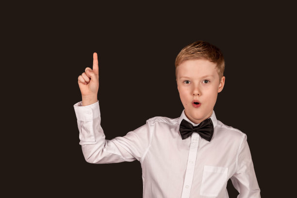 学生在白色衬衫领结食指向上看在黑色孤立的背景相机。好主意，我找到了。时尚的小男孩学生在工作室摆姿势。复制广告的文本空间图片下载