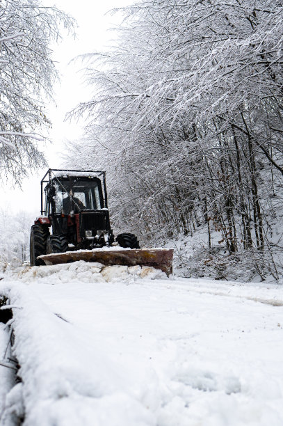 一辆拖拉机在喀尔巴阡山脉的山路上铲雪。图片下载