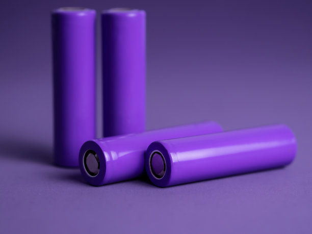 电池。圆柱形电池，18650型，紫色背景。用于电器和设备的可充电锂离子电池。图片下载