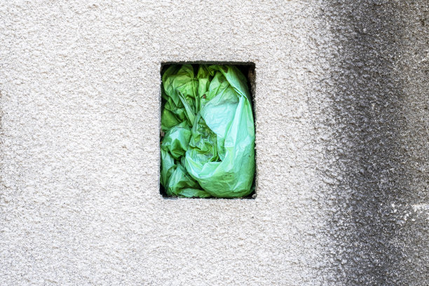 混凝土墙，矩形洞内有垃圾袋图片下载