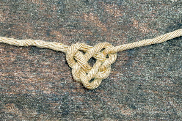 剑麻绳粘在木制背景上。心形结。爱的象征。情人节的概念图片下载
