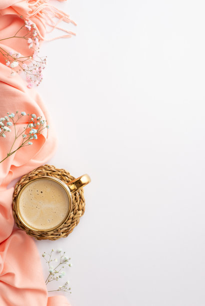 你好，春天概念。俯视图垂直照片的一杯新鲜的咖啡在藤条服务席粉红色围巾和石膏花孤立的白色背景与复制空间图片下载