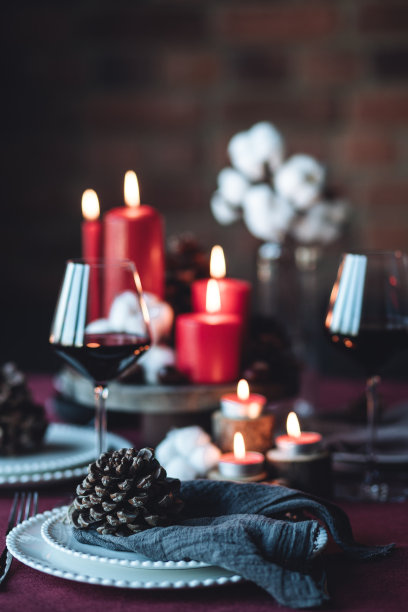 圣诞或新年家庭晚餐的乡村餐桌装饰。中心装饰有红蜡烛，干橙，圆锥体，肉桂，八角。零废物环保之家。舒适的氛围，黑色的背景。近距离图片下载