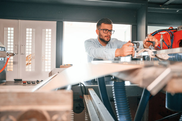 板材切割机。操作设备。穿着白色衣服的印刷厂工人在室内图片下载