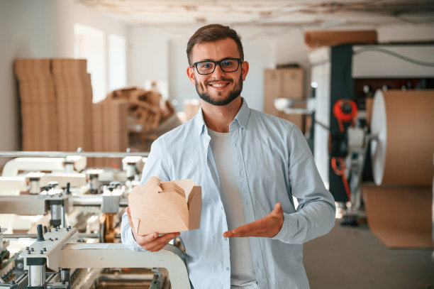 手持并展示木板。穿着白色衣服的印刷厂工人在室内图片下载