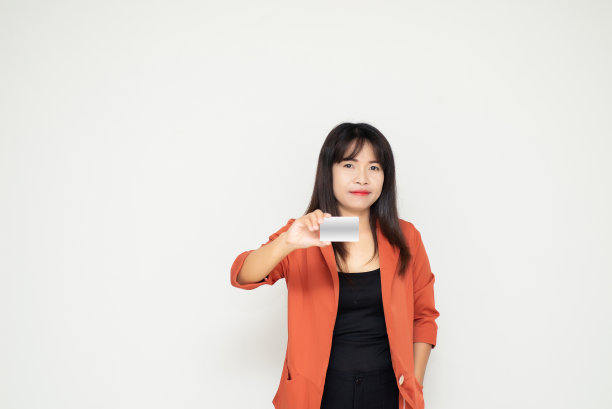 有吸引力的亚洲商业妇女持有空白白色模拟卡在手对白色混凝土墙背景在办公室。图片下载