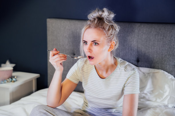 震惊，压力，惊讶的女人吃着冰淇淋，拿着遥控器在床上看电视。恐怖的恐怖电影或可怕的新闻，她眼中的恐惧暴饮暴食，消极情绪的干扰图片下载