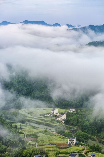 美丽的乡村风景在一个山谷，一个小村庄被雾覆盖，中国图片下载
