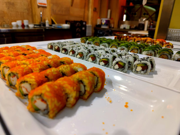 在一家亚洲自助餐厅的白色盘子上，摆放着各种颜色的寿司，里面有肉、蔬菜和鱼图片下载