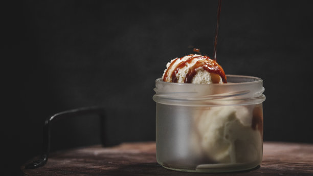 特写镜头的冰淇淋勺子与焦糖酱隔离在黑色背景图片下载