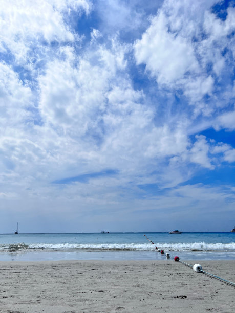 在多云的天空下，海滩和蓝色的大海和白色的海浪。图片下载