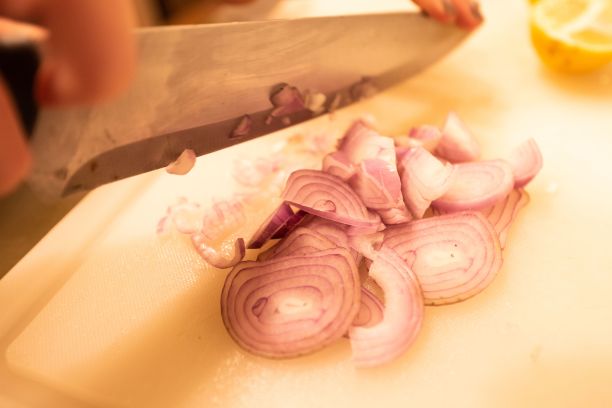 女人，在厨房的砧板上切洋葱片，这是做饭的概念图片下载