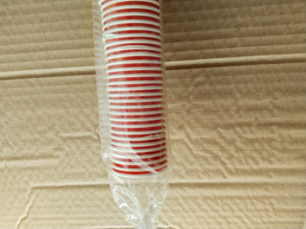 堆叠的红色一次性杯子孤立的棕色背景。这是粉红色纸玻璃的孤立景象。是一堆玻璃杯。图片下载