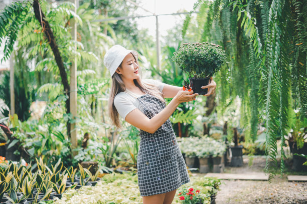 年轻的女人做爱好照顾植物，浇水，铲花。在花园里休息的时候图片下载