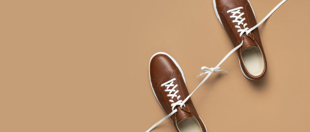 皮革棕色男子运动鞋与白色鞋带和米色背景橡胶鞋底。平铺顶视图。男士运动休闲鞋。时尚的运动鞋。男性时尚潮人鞋简约的背景图片下载