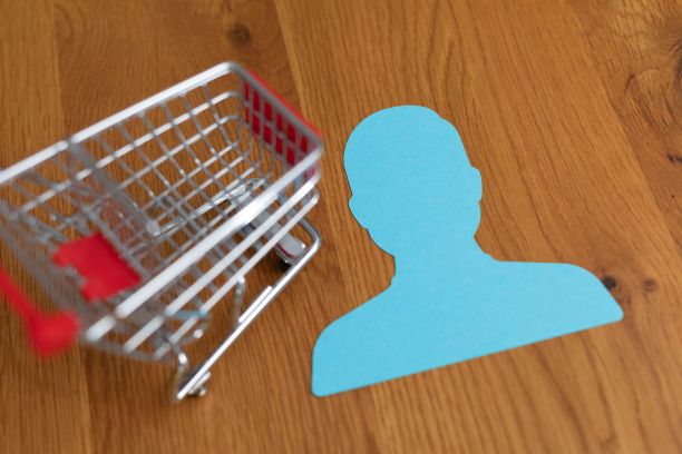 木桌上的迷你购物车的高角度特写，上面有一个蓝色的纸人牌。图片下载