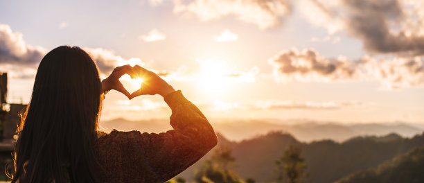 年轻女子旅行者在日出的山脉和美丽的风景做心形符号，旅行的生活方式理念图片下载