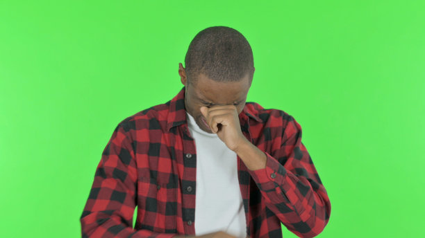 悲伤的非洲男子在绿色背景上哭泣图片下载