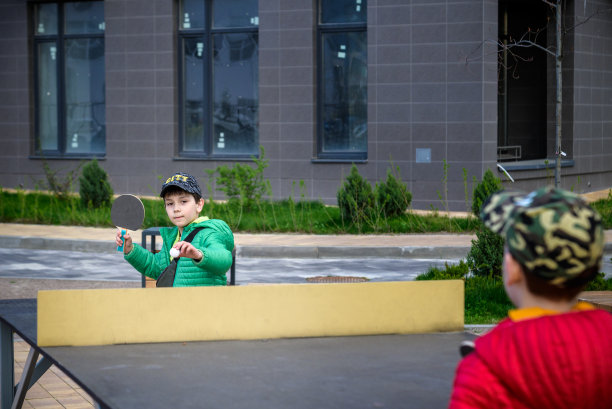 两个快乐的男孩，十几岁的双胞胎兄弟，享受假期在户外打乒乓球。儿童积极休闲理念图片下载