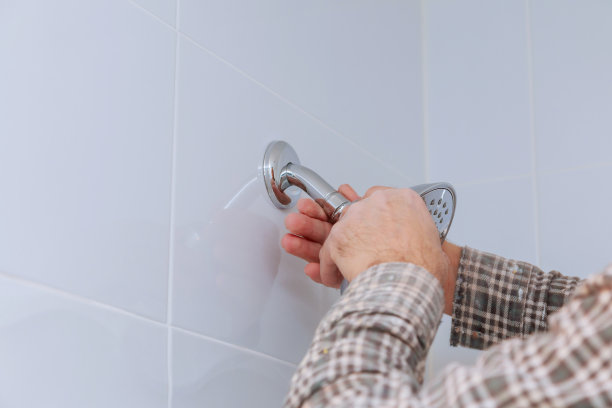 管道工在浴室更换高度可调的淋浴头，淋浴架安装在墙上。图片下载