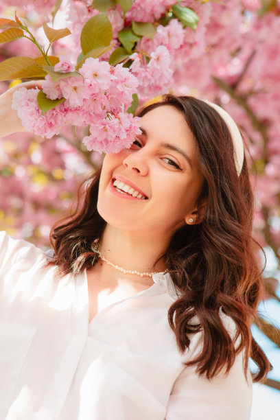 华丽温柔的高加索女人在盛开的粉红色樱花树下图片下载
