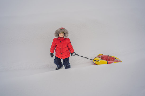 孩子们在雪地上玩得很开心。男孩正在骑管子。孩子们的冬季乐趣图片下载