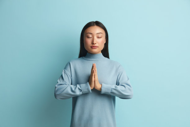 平和的女人在工作室冥想。亚洲年轻女孩做祈祷手势图片下载