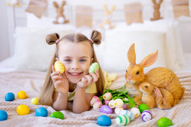 复活节，一个小女孩带着彩绘的彩蛋、郁金香和一只兔子在家里明亮的房间里微笑着为假期做准备，闭上眼睛玩彩蛋玩得很开心图片下载