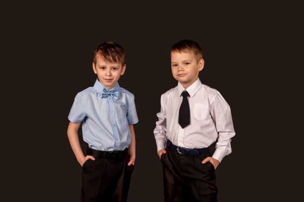 两个穿着白色和蓝色衬衫的自信认真的男孩朋友在黑色背景上孤立地看着相机摆姿势。在摄影棚里拍摄时髦的男孩和孩子。教育时尚理念。复制文本空格图片下载