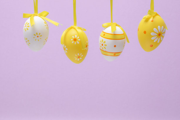 复活节彩蛋挂在紫色背景的丝带上。照片。图片下载