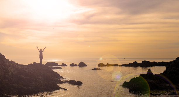 幸福的女人，日落时的大海和岩石图片下载