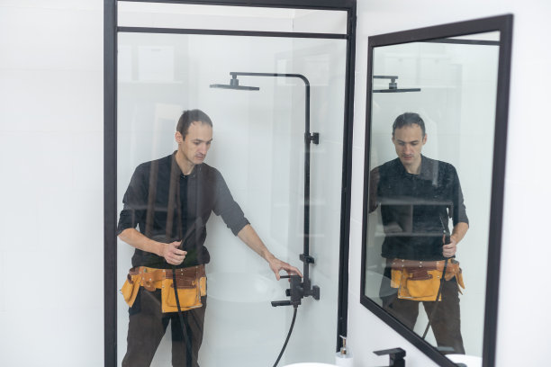 年轻的水管工正在修理淋浴房。图片下载